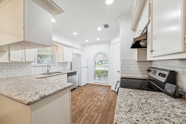 kitchen with white cabinets, sink, light stone countertops, appliances with stainless steel finishes, and light hardwood / wood-style floors