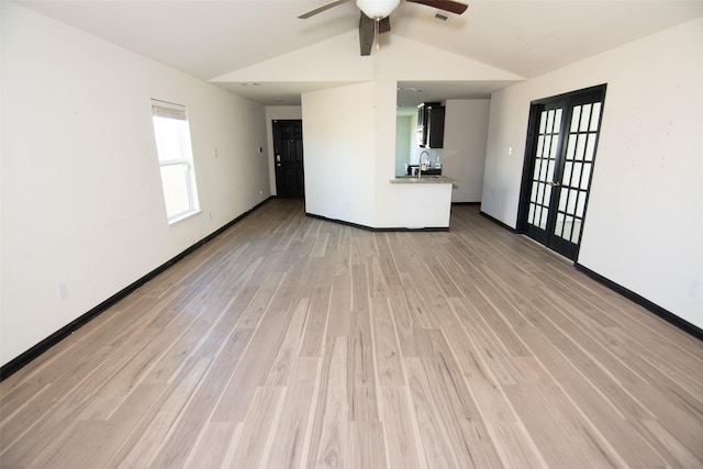 unfurnished living room featuring ceiling fan, french doors, sink, light hardwood / wood-style floors, and lofted ceiling