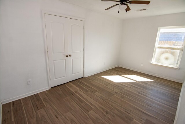 unfurnished bedroom featuring a closet, ceiling fan, and dark wood-type flooring