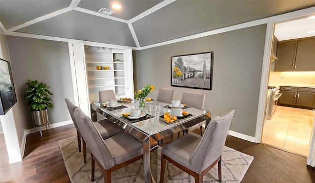 dining room featuring crown molding, dark wood-type flooring, and vaulted ceiling