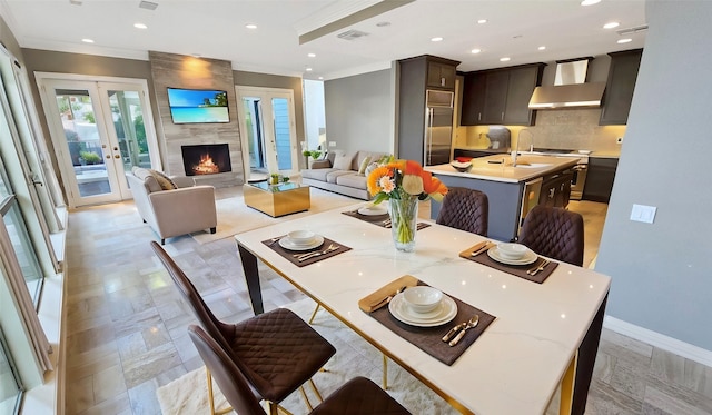 dining area featuring sink, crown molding, a fireplace, and french doors