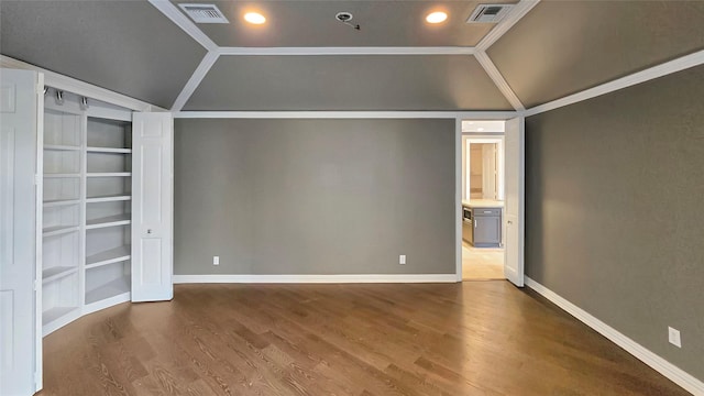 unfurnished room featuring built in features, wood-type flooring, crown molding, and lofted ceiling