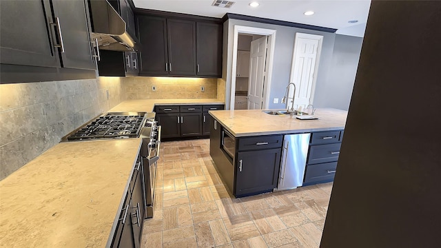 kitchen featuring stainless steel appliances, tasteful backsplash, wall chimney exhaust hood, and sink