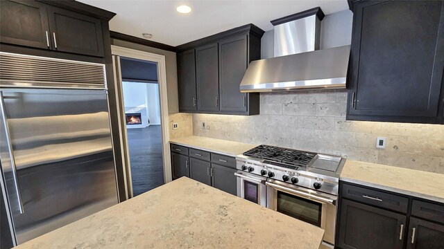 kitchen featuring high quality appliances, ornamental molding, decorative backsplash, and wall chimney exhaust hood