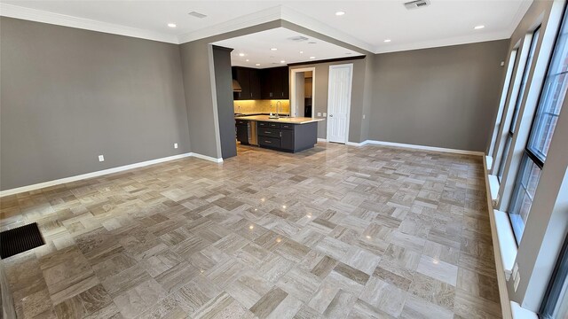 unfurnished living room featuring sink, light parquet floors, and ornamental molding