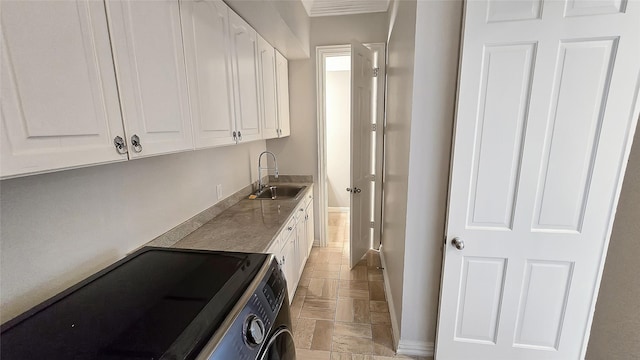 clothes washing area featuring washer and clothes dryer, cabinets, and sink