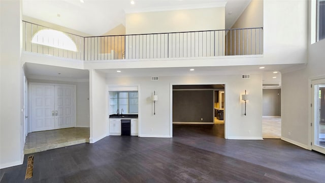 unfurnished living room featuring a wealth of natural light, high vaulted ceiling, and dark hardwood / wood-style floors