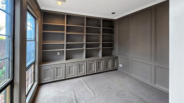 carpeted spare room featuring built in shelves and crown molding