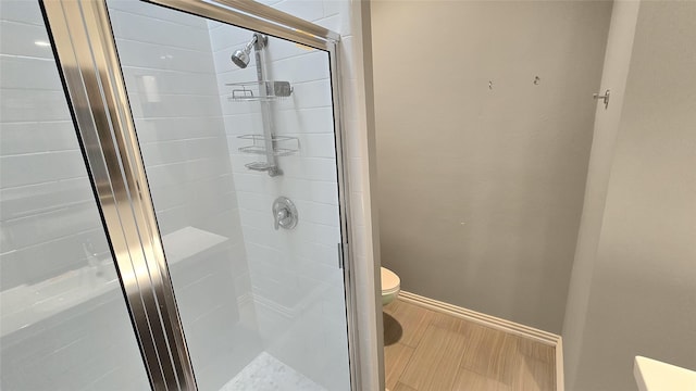 bathroom featuring toilet and a shower with shower door