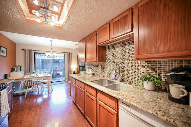 kitchen with sink, dark wood-type flooring, a notable chandelier, pendant lighting, and a textured ceiling