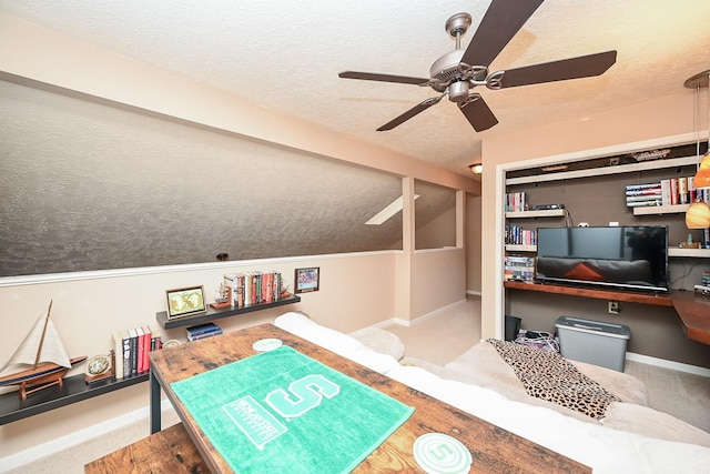 rec room with carpet flooring, ceiling fan, built in desk, and a textured ceiling