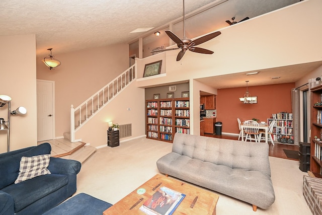 carpeted living room with ceiling fan, a towering ceiling, and a textured ceiling
