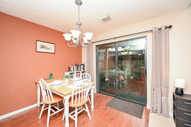 dining space featuring an inviting chandelier, a textured ceiling, and hardwood / wood-style flooring