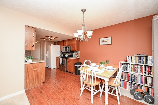 dining room featuring light hardwood / wood-style floors, a textured ceiling, and a chandelier