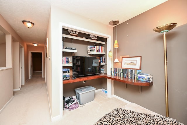 office area with built in desk, light colored carpet, and a textured ceiling