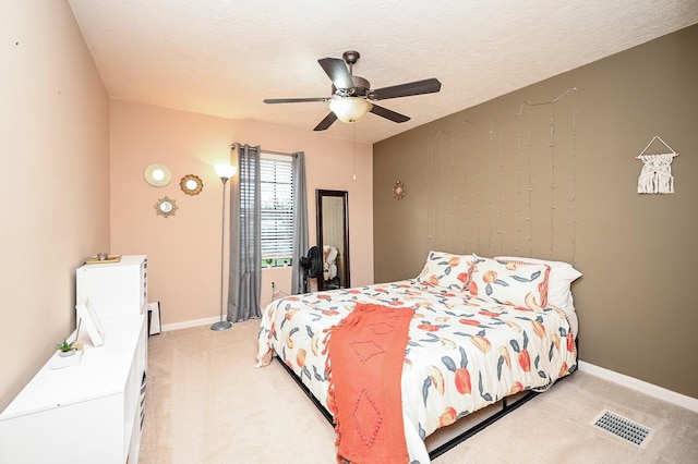 carpeted bedroom featuring ceiling fan and a textured ceiling