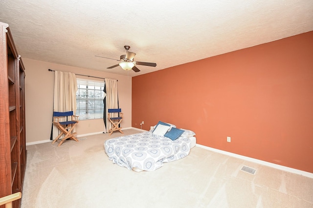 bedroom with a textured ceiling, carpet floors, and ceiling fan