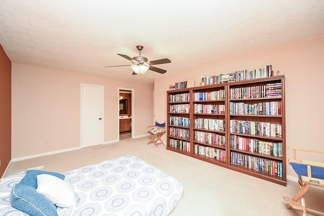 sitting room with a textured ceiling, light colored carpet, and ceiling fan