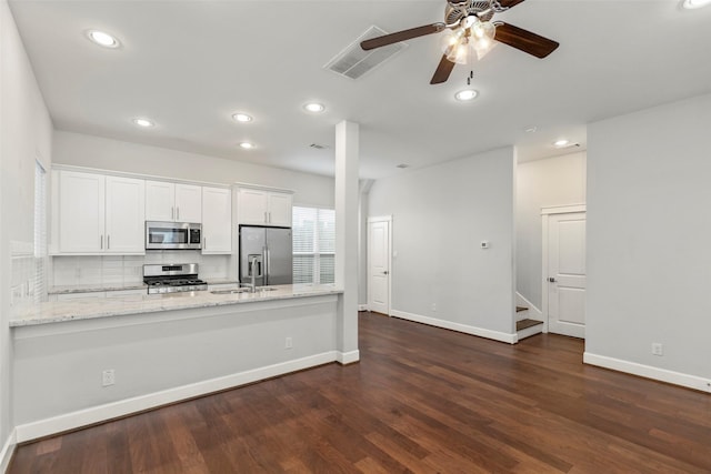 kitchen featuring light stone countertops, appliances with stainless steel finishes, dark hardwood / wood-style flooring, ceiling fan, and white cabinetry