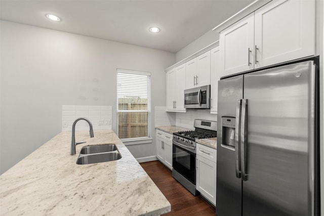 kitchen featuring light stone countertops, sink, dark hardwood / wood-style floors, white cabinets, and appliances with stainless steel finishes