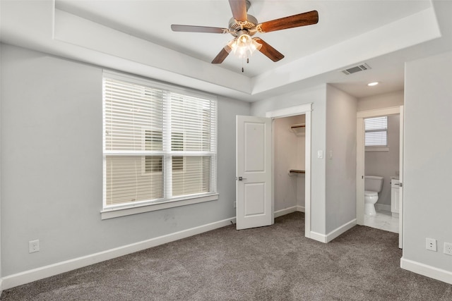 unfurnished bedroom featuring ensuite bathroom, a walk in closet, carpet flooring, ceiling fan, and a closet