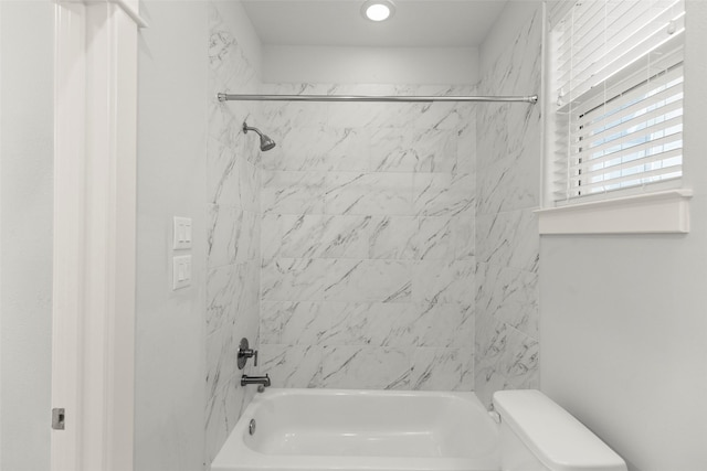 bathroom with toilet and tiled shower / bath