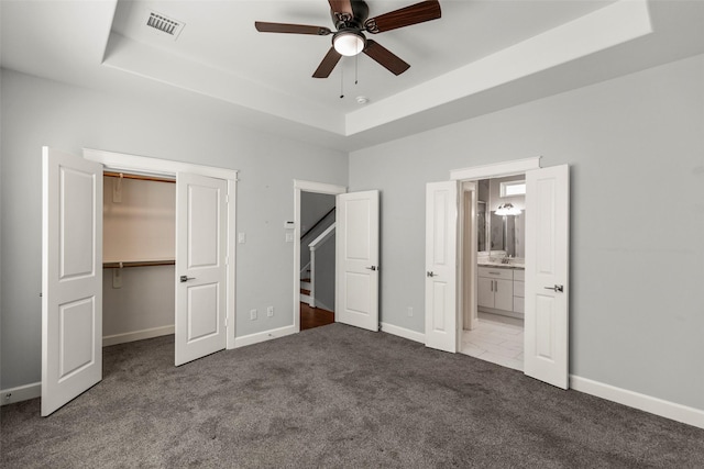 unfurnished bedroom featuring carpet, a raised ceiling, and ceiling fan