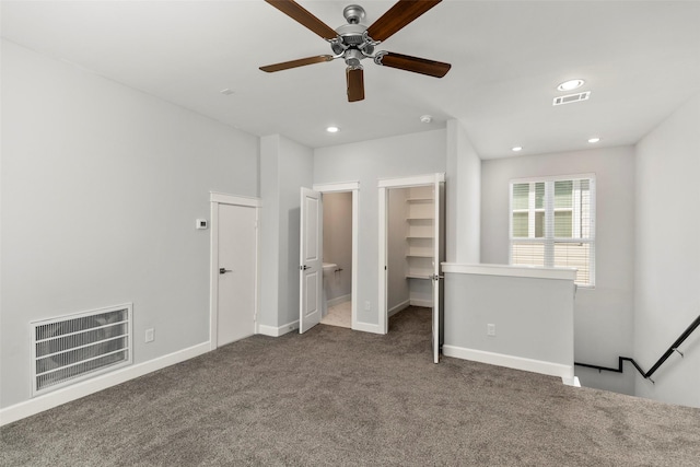 unfurnished bedroom with a walk in closet, ceiling fan, a closet, and carpet