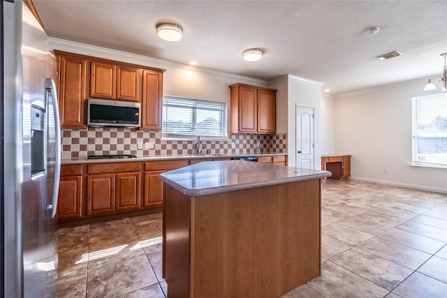 kitchen featuring hanging light fixtures, a center island, stainless steel appliances, and a wealth of natural light