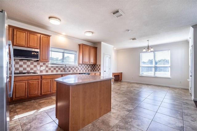 kitchen with backsplash, an inviting chandelier, hanging light fixtures, appliances with stainless steel finishes, and a kitchen island