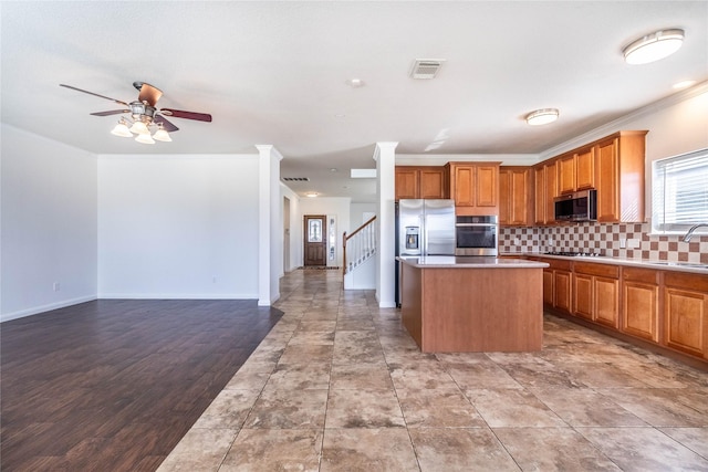 kitchen with sink, crown molding, light wood-type flooring, a kitchen island, and stainless steel appliances