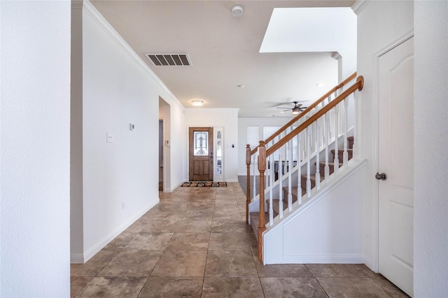 foyer entrance featuring tile patterned flooring, ceiling fan, and crown molding