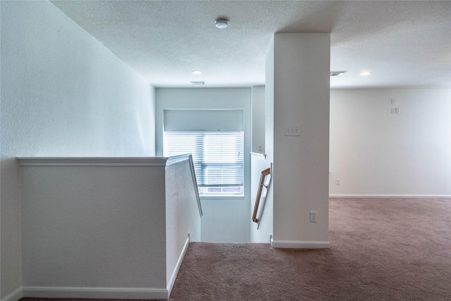 hallway with carpet and a textured ceiling