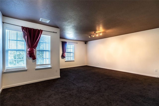 carpeted empty room with a textured ceiling and track lighting