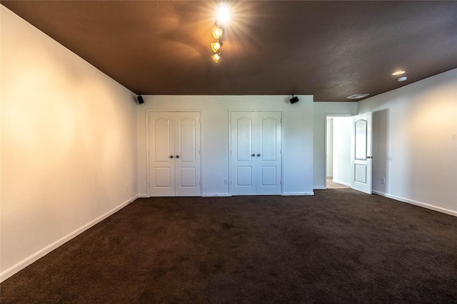 unfurnished bedroom with two closets and dark carpet