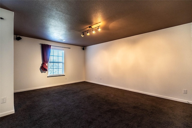 carpeted spare room featuring track lighting and a textured ceiling