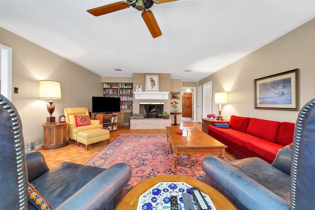 living room featuring ceiling fan, a fireplace, and a textured ceiling