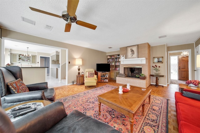 living room featuring a fireplace, ceiling fan with notable chandelier, a textured ceiling, and light parquet floors