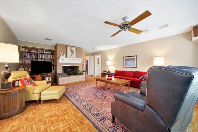 living room featuring a textured ceiling, a brick fireplace, ceiling fan, and light parquet flooring