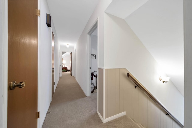 hallway with light colored carpet and vaulted ceiling