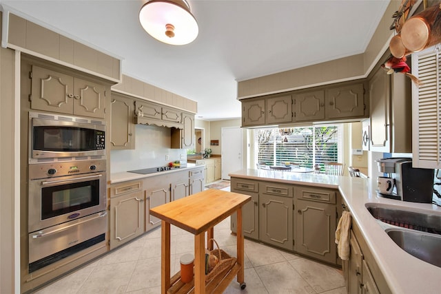 kitchen with crown molding, sink, light tile patterned flooring, and appliances with stainless steel finishes