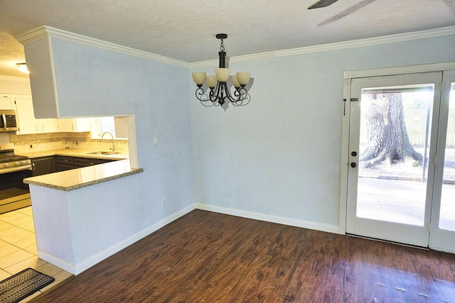 kitchen featuring stove, sink, white cabinets, hardwood / wood-style floors, and hanging light fixtures