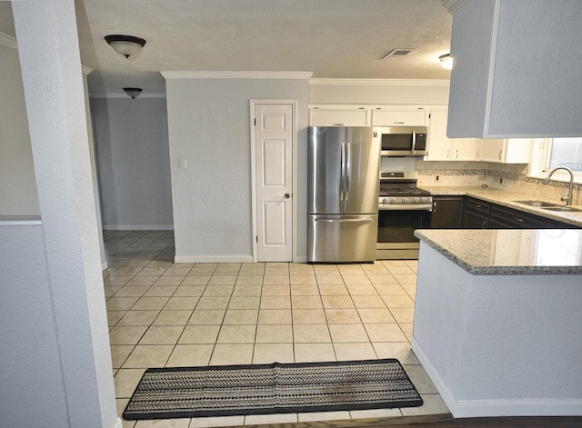 kitchen with light stone countertops, ornamental molding, stainless steel appliances, sink, and white cabinetry