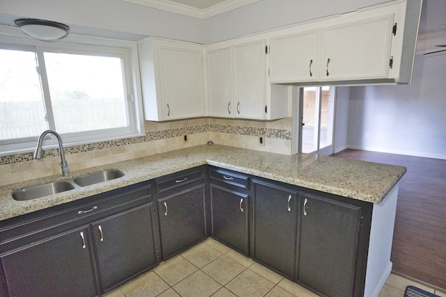 kitchen featuring white cabinets, light tile patterned floors, crown molding, and sink