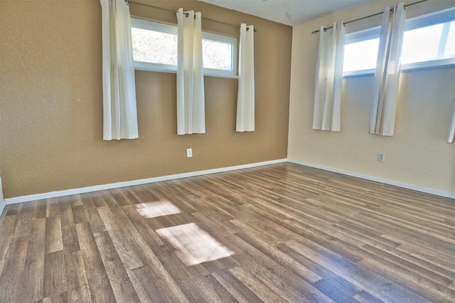 empty room with a wealth of natural light and dark wood-type flooring