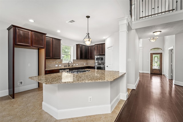 kitchen featuring a center island, stainless steel appliances, light stone counters, backsplash, and light wood-type flooring