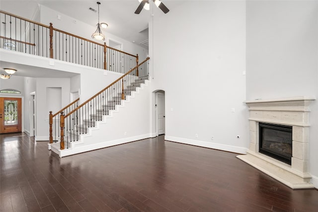 unfurnished living room with dark hardwood / wood-style floors, ceiling fan, and a towering ceiling