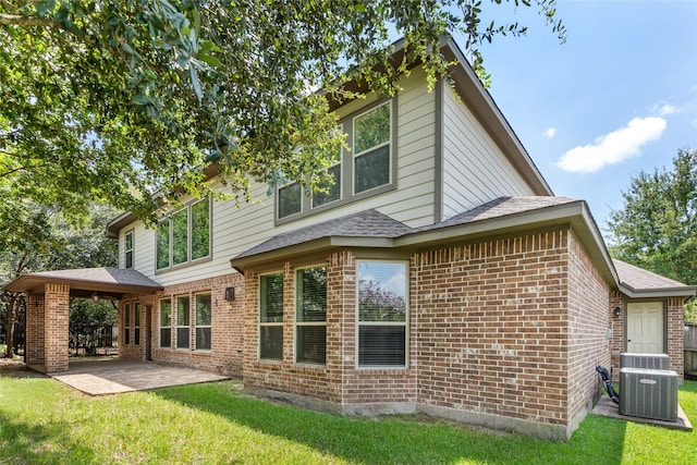 rear view of house featuring central AC unit, a yard, and a patio