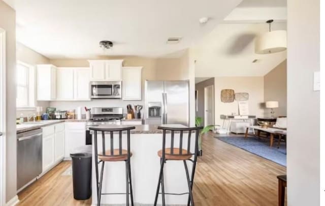 kitchen with white cabinetry, light wood-type flooring, stainless steel appliances, and a breakfast bar area