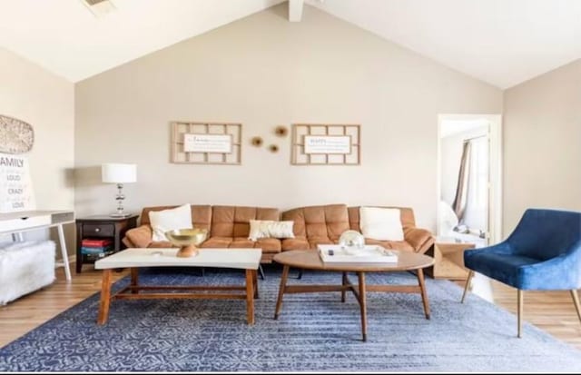 living room with hardwood / wood-style floors and vaulted ceiling with beams